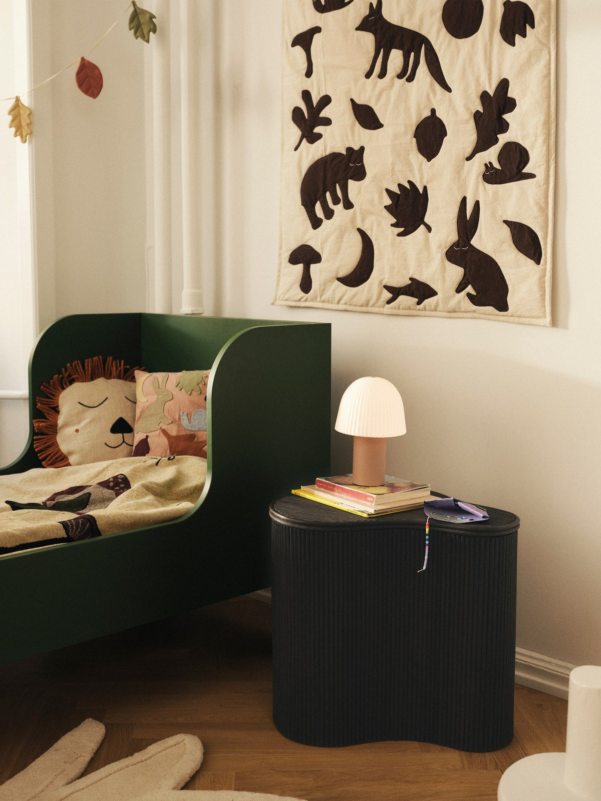 Wolldecke Lunden von Ferm Living in Off-White mit dunkelschokoladefarbenen Applikationen aus Waldtieren, gefertigt aus Bio-Baumwolle.