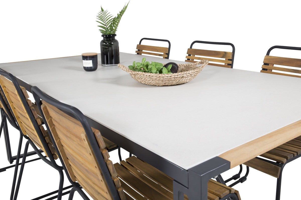 Rechteckiger Gartentisch mit schwarzer Glasplatte und Teakholz-Elementen, dazu zwei Esszimmerstühle mit Teakholz-Optik und Stahlgestell im Freien.