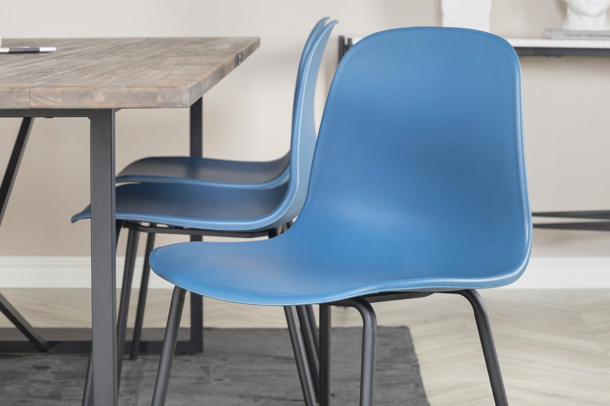 Esstisch Padang mit Teak-Tischplatte in Natur und Stahlbeinen, kombiniert mit blauen Arctic Stühlen mit schwarz pulverbeschichtetem Gestell.