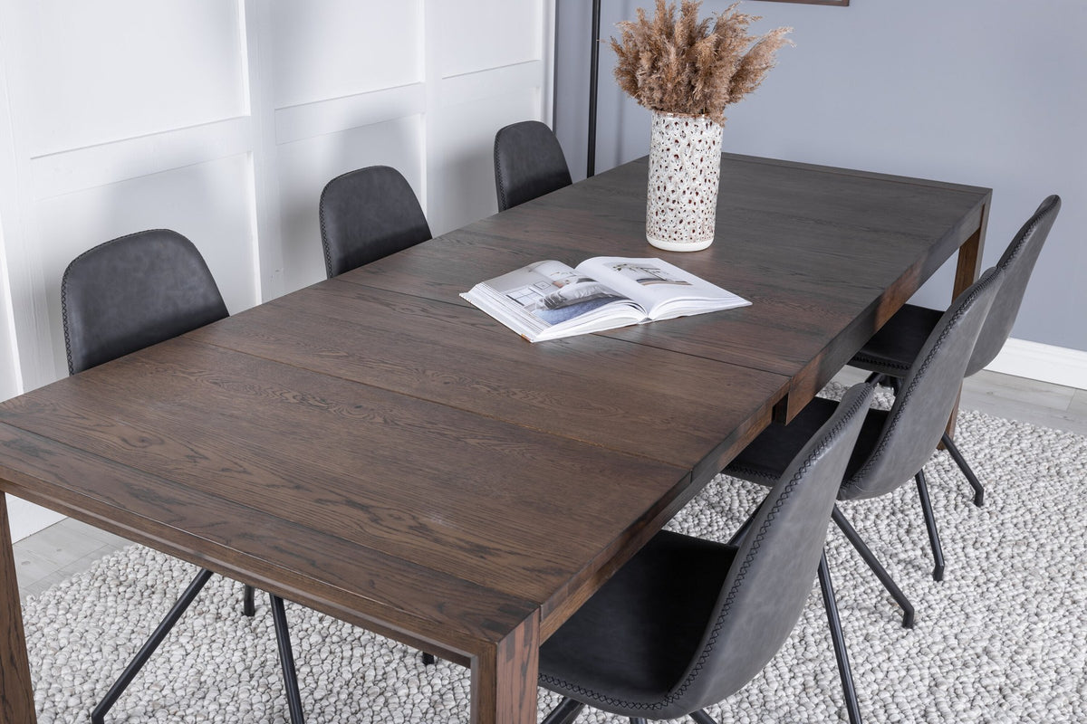 Rechteckiger Esstisch aus Eiche in Natur mit ausziehbarer Platte, dazu zwei schwarze Esszimmerstühle mit gepolsterter Sitzfläche von Venture Home.