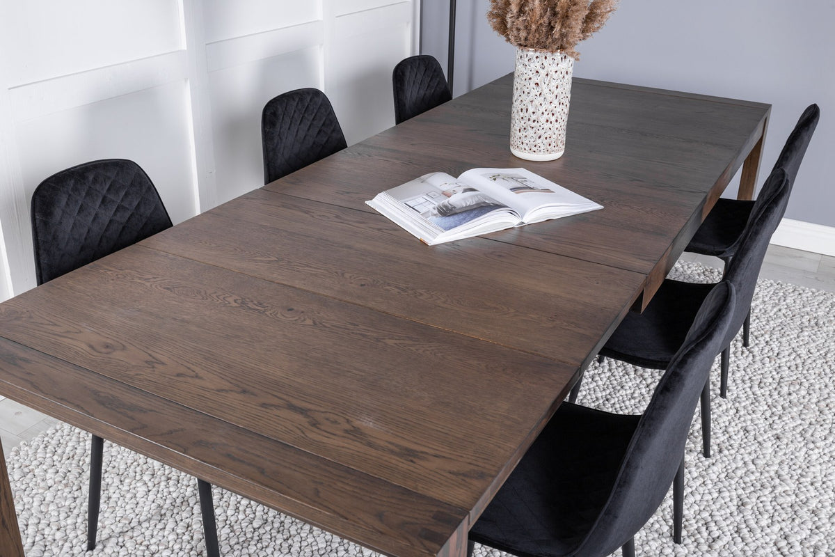 Rechteckiger Esstisch aus Eiche in Natur mit ausziehbarer Platte, dazu zwei schwarze Esszimmerstühle mit gepolsterter Sitzfläche von Venture Home.