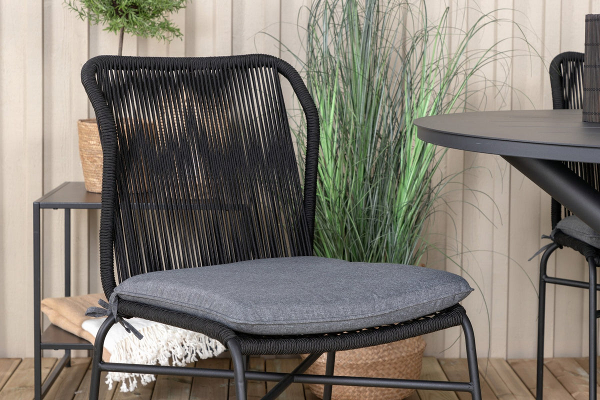 Runder Aluminium-Esstisch Ø120 cm in Schwarz mit Kreuzgestell und vier gepolsterten Esszimmerstühlen aus schwarzem Stahl, stapelbar, für den Outdoor-Bereich.