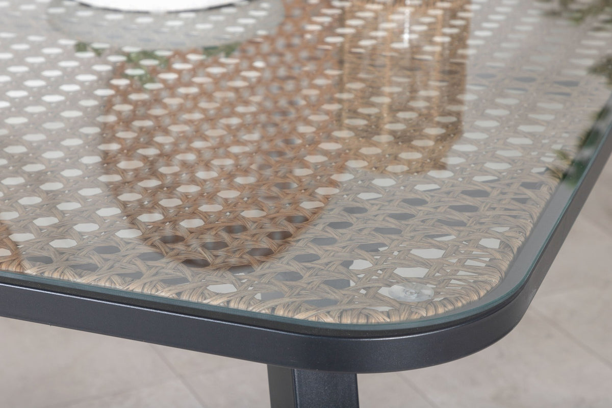 Gartentischset Paola mit schwarzem Stahlgestell und Weidengeflecht-Tischplatte sowie sechs stapelbaren Lindos-Stühlen aus schwarzem Aluminium und Polyesterseil.