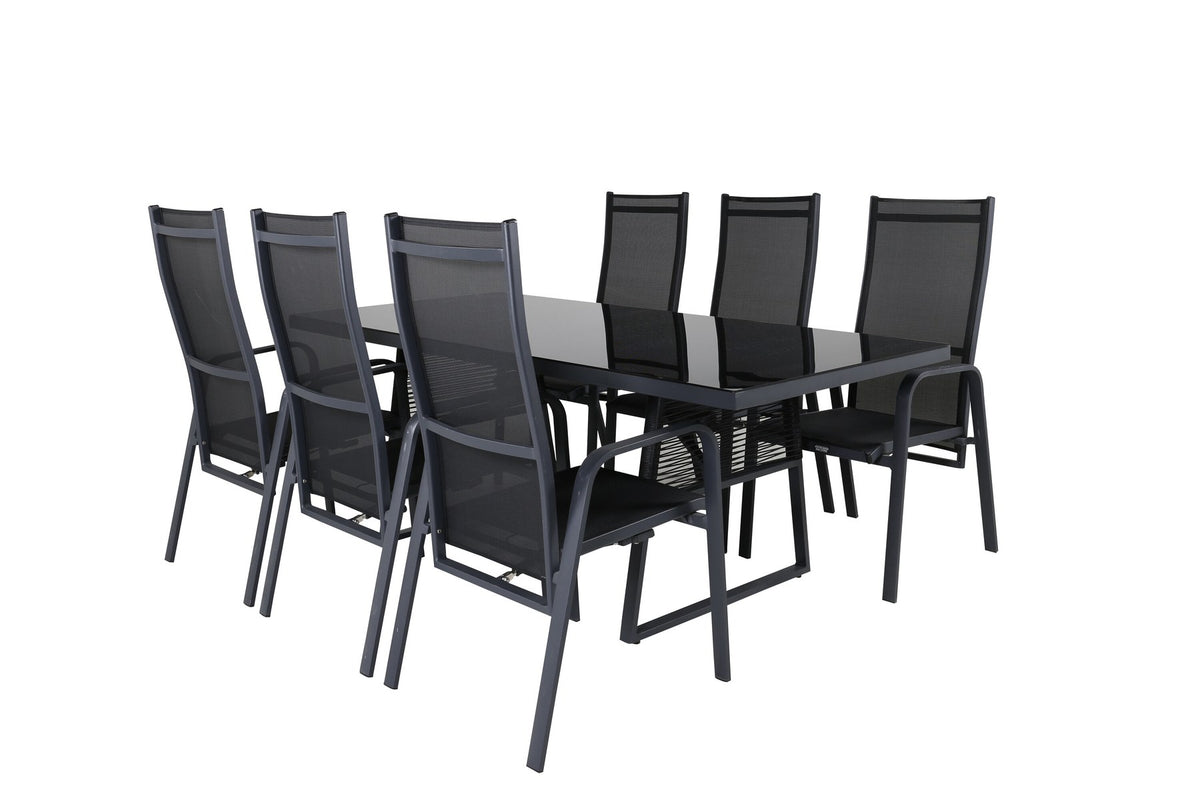 Foto eines rechteckigen Esstisches aus schwarzem Glas mit Aluminiumbeinen und zwei schwarzen Relaxsesseln aus Geflecht im Freien.