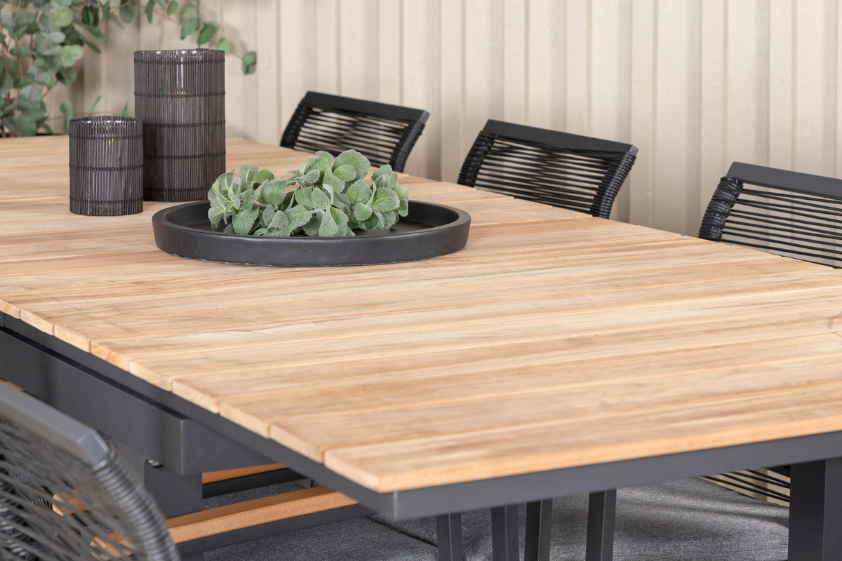 Foto eines schwarzen 2er-Stuhlsets mit Aluminiumgestell und Polyesterbezug neben einem rechteckigen Teak-Esstisch in Natur mit Stahlbeinen.