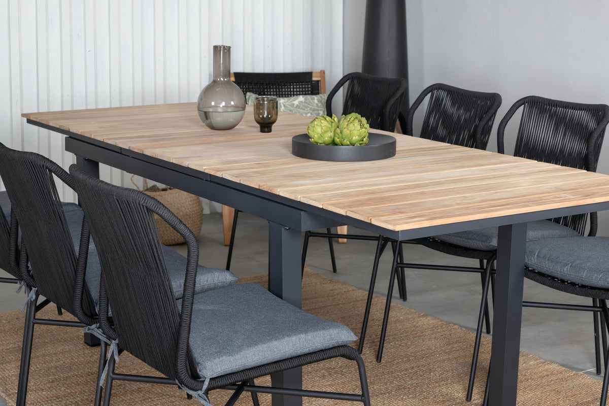 Vier schwarze Esszimmerstühle aus Aluminium mit Seilbezug und ausziehbarer rechteckiger Teakholz-Esstisch mit Stahlbeinen, Naturfarben.