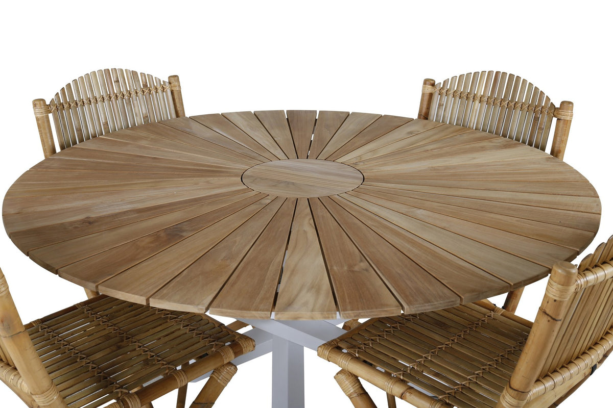 Runder Esstisch ⌀140 aus Teakholz mit Rattanbeinen neben Caféstuhl mit Aluminiumgestell und Bezug aus Baumwolle und Polyester in Naturfarbe.