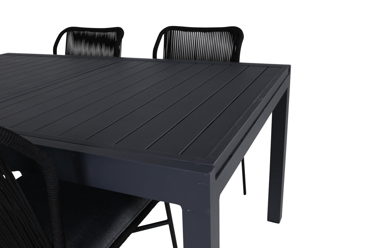 Vier schwarze Esszimmerstühle mit Polyesterbezug und pulverbeschichtetem Aluminiumgestell neben einem rechteckigen Esstisch aus schwarzem Aluminium.