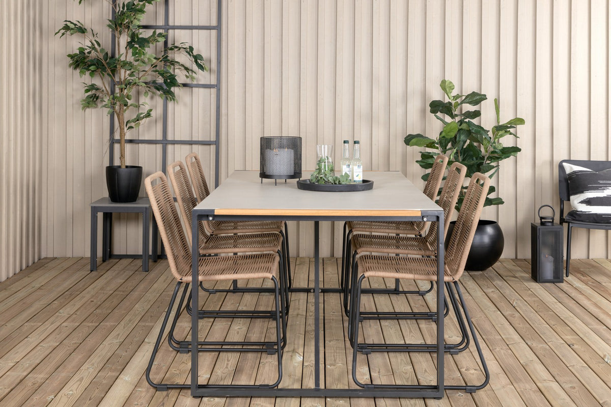 Zwei braune Esszimmerstühle mit Teakholz und Aluminium neben einem rechteckigen Glastisch mit schwarzer Tischplatte und Stahlbeinen im Aussenbereich.