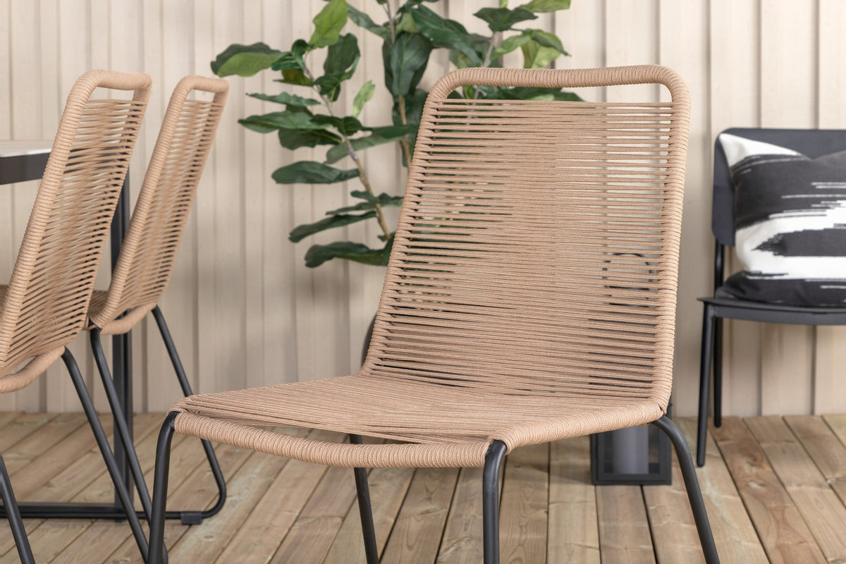Zwei braune Esszimmerstühle mit Teakholz und Aluminium neben einem rechteckigen Glastisch mit schwarzer Tischplatte und Stahlbeinen im Aussenbereich.
