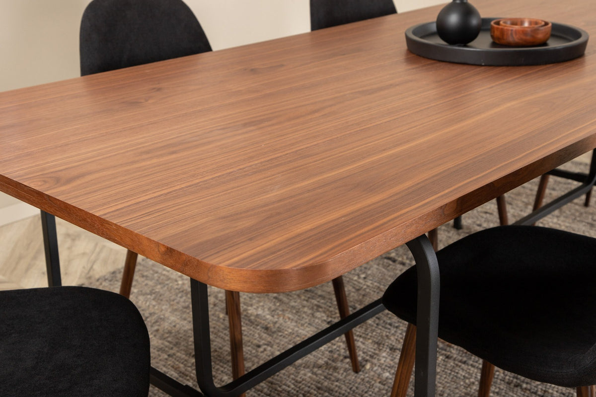 Rechteckiger Esstisch mit Nussbaum-Furnierplatte aus MDF und schwarzem Stahluntergestell, umgeben von sechs gepolsterten Polar Stühlen mit schwarzem Polyesterbezug.