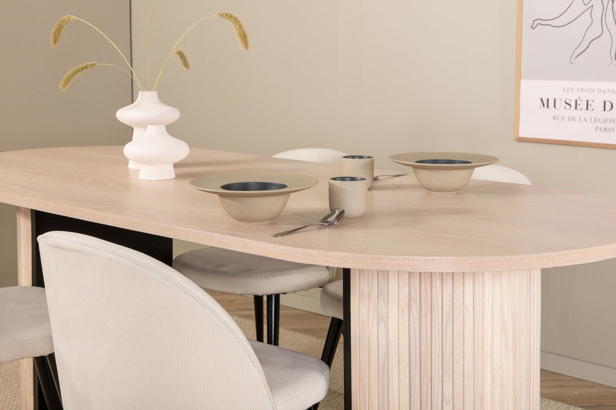 Ovaler Esstisch mit weiss lasierter MDF-Tischplatte und vier Samtstühlen mit schwarzen Stahlbeinen, cremefarbenes Esszimmerset.
