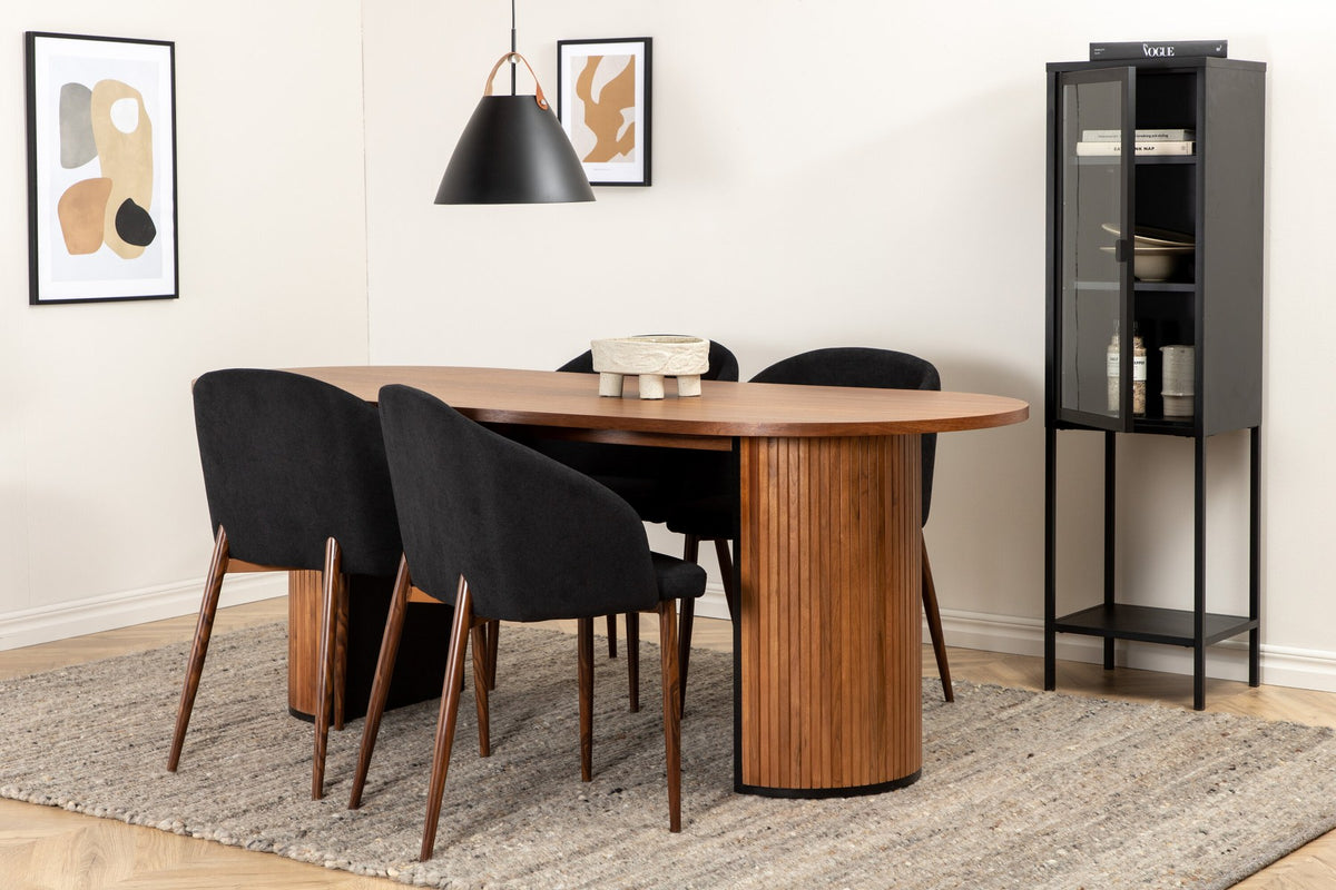 Ovaler Esstisch mit Nussbaum-MDF-Furnierplatte und Stahlgestell, daneben zwei schwarze Polsterstühle mit Metallbeinen im Esszimmer.