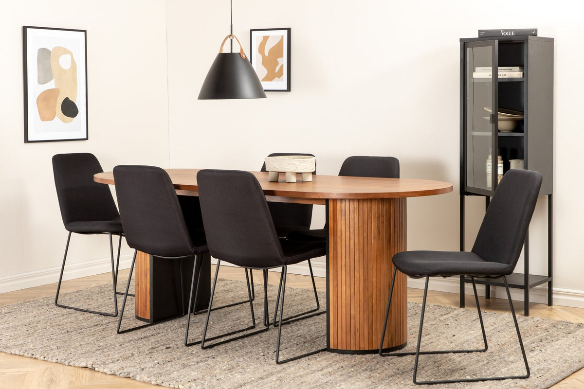 Ovaler Esstisch mit Nussbaum-Furnier und MDF-Platte, kombiniert mit zwei schwarzen Esszimmerstühlen mit Polyesterbezug und schmalen Stahlbeinen.