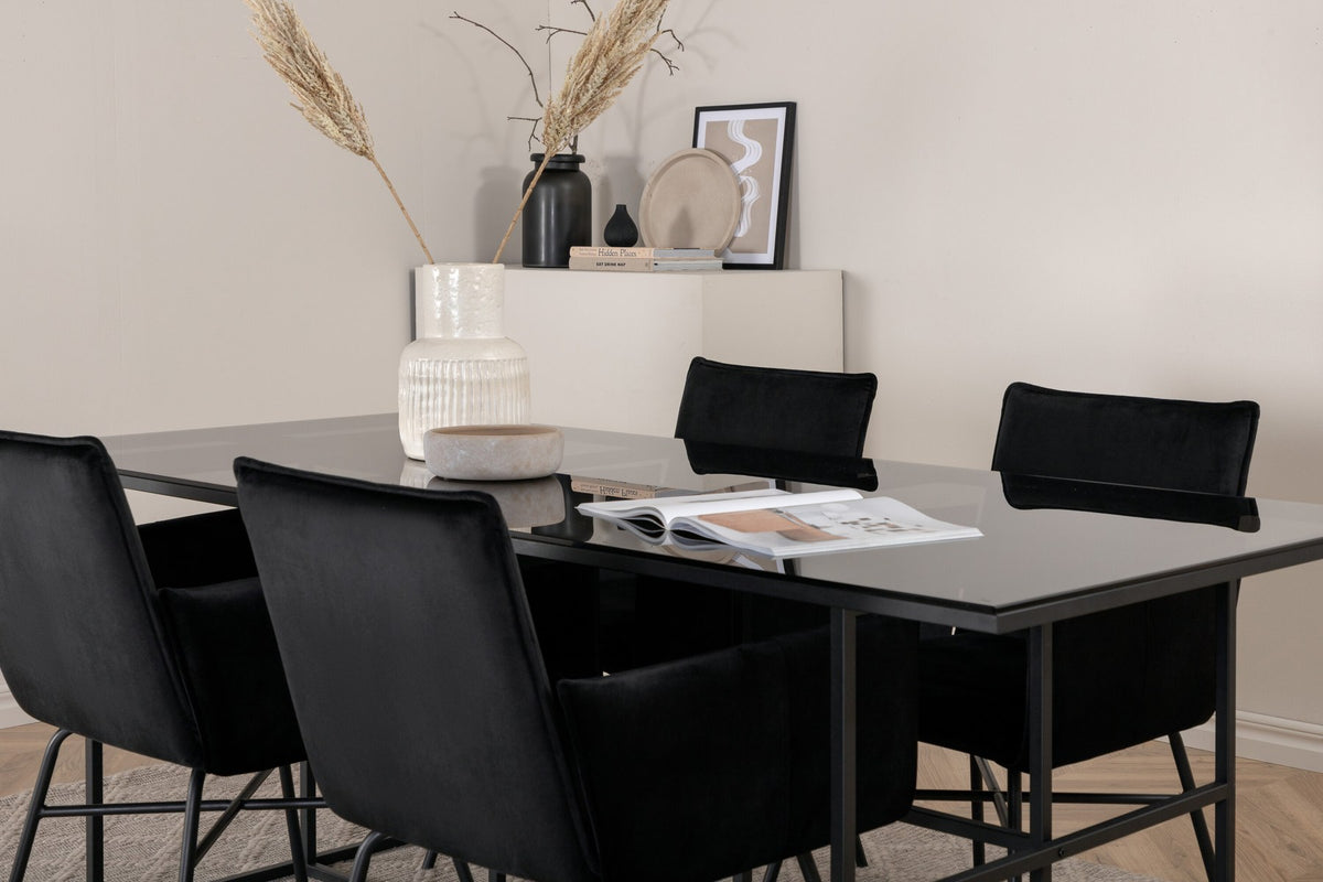 Rechteckiger Esstisch mit rauchschwarzer Glasplatte und schwarzem Metallgestell, umgeben von vier Esszimmerstühlen mit Samtbezug in Schwarz.