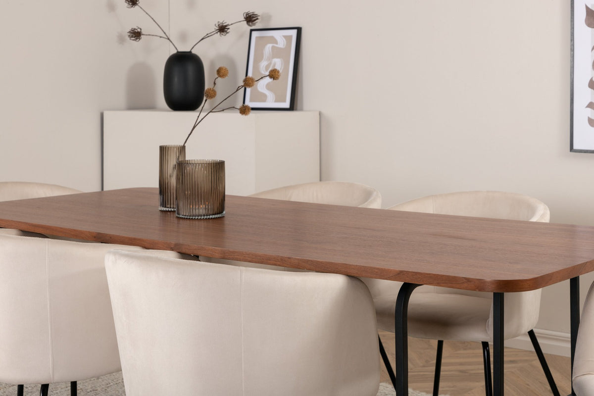 Esstisch mit Platte aus MDF und Walnussfurnier, schwarzem Metallgestell, kombiniert mit sechs Berit-Stühlen aus beigem Samtstoff und schwarzen Beinen.