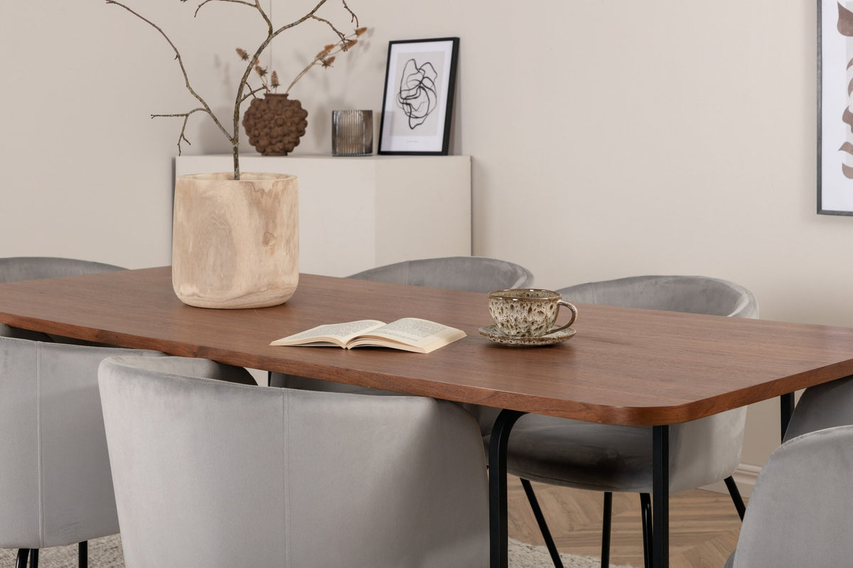 Esstisch mit Platte aus MDF und Walnussfurnier, schwarzem Metallgestell, kombiniert mit sechs Berit-Stühlen aus beigem Samtstoff und schwarzen Beinen.