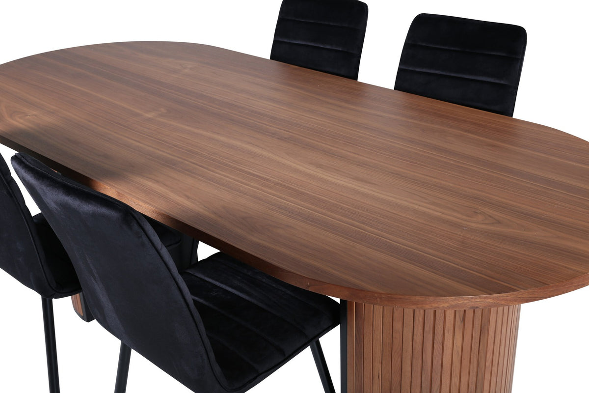 Ovaler Esstisch mit Nussbaum-Tischplatte aus MDF und Furnier sowie zwei schwarze Esszimmerstühle mit Samtsitz und schmalen Beinen.