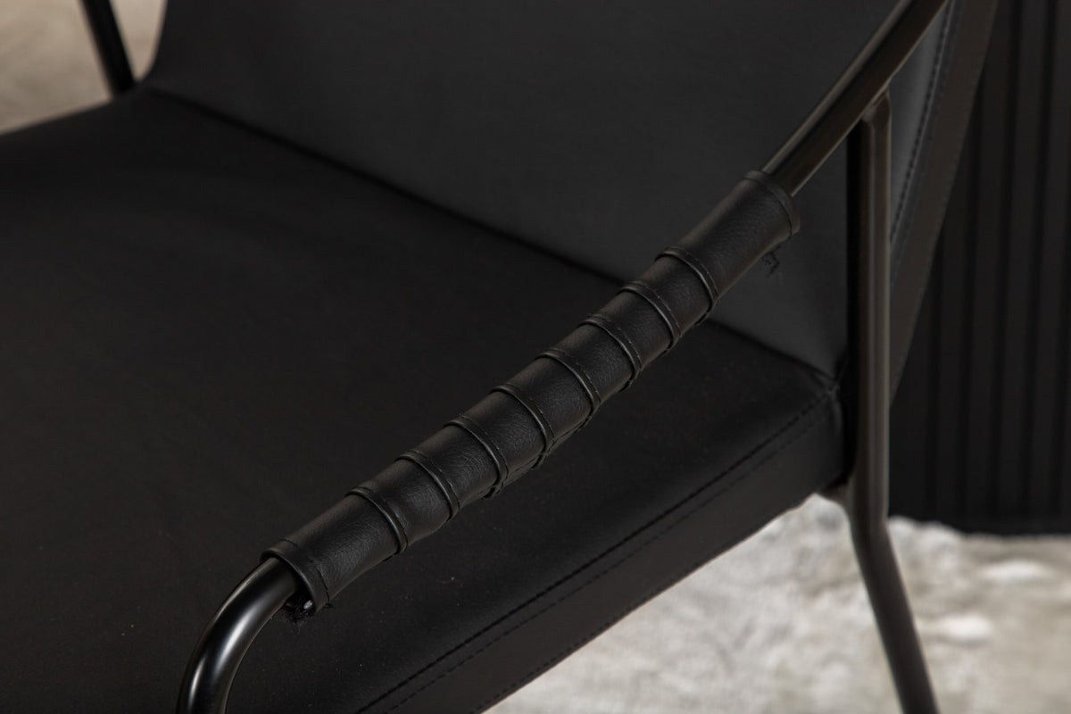 Zwei schwarze Esszimmerstühle mit Beinen aus Eisen und Sitzfläche aus Polyurethan-Membran neben ovalem MDF-Esstisch in Schwarz.
