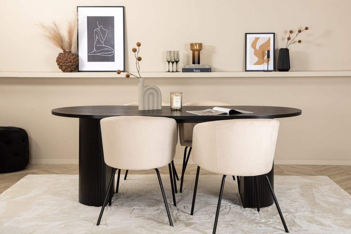 Ovaler Esstisch Bianca mit schwarzer MDF-Furnier-Platte und geripptem Gestell, umgeben von vier Berit-Stühlen mit beigem Samtsitz und schwarzen Metallbeinen.
