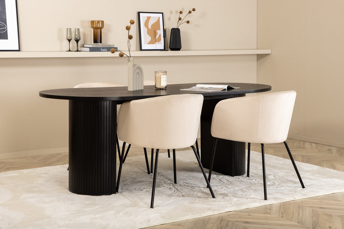 Ovaler Esstisch Bianca mit schwarzer MDF-Furnier-Platte und geripptem Gestell, umgeben von vier Berit-Stühlen mit beigem Samtsitz und schwarzen Metallbeinen.