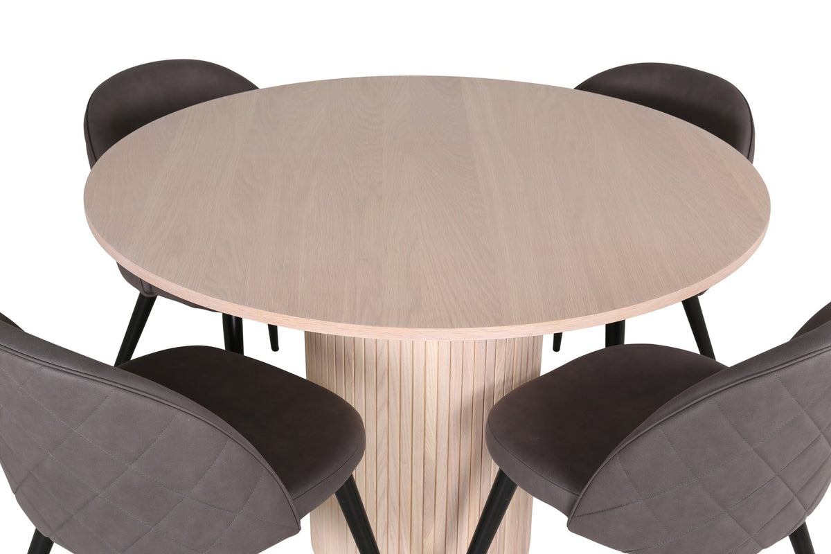 Runder Esstisch aus MDF in Whitewash mit ⌀110cm neben zwei Esszimmerstühlen mit grauem Mikrofaserstoff und schwarz pulverbeschichteten Eisenbeinen.