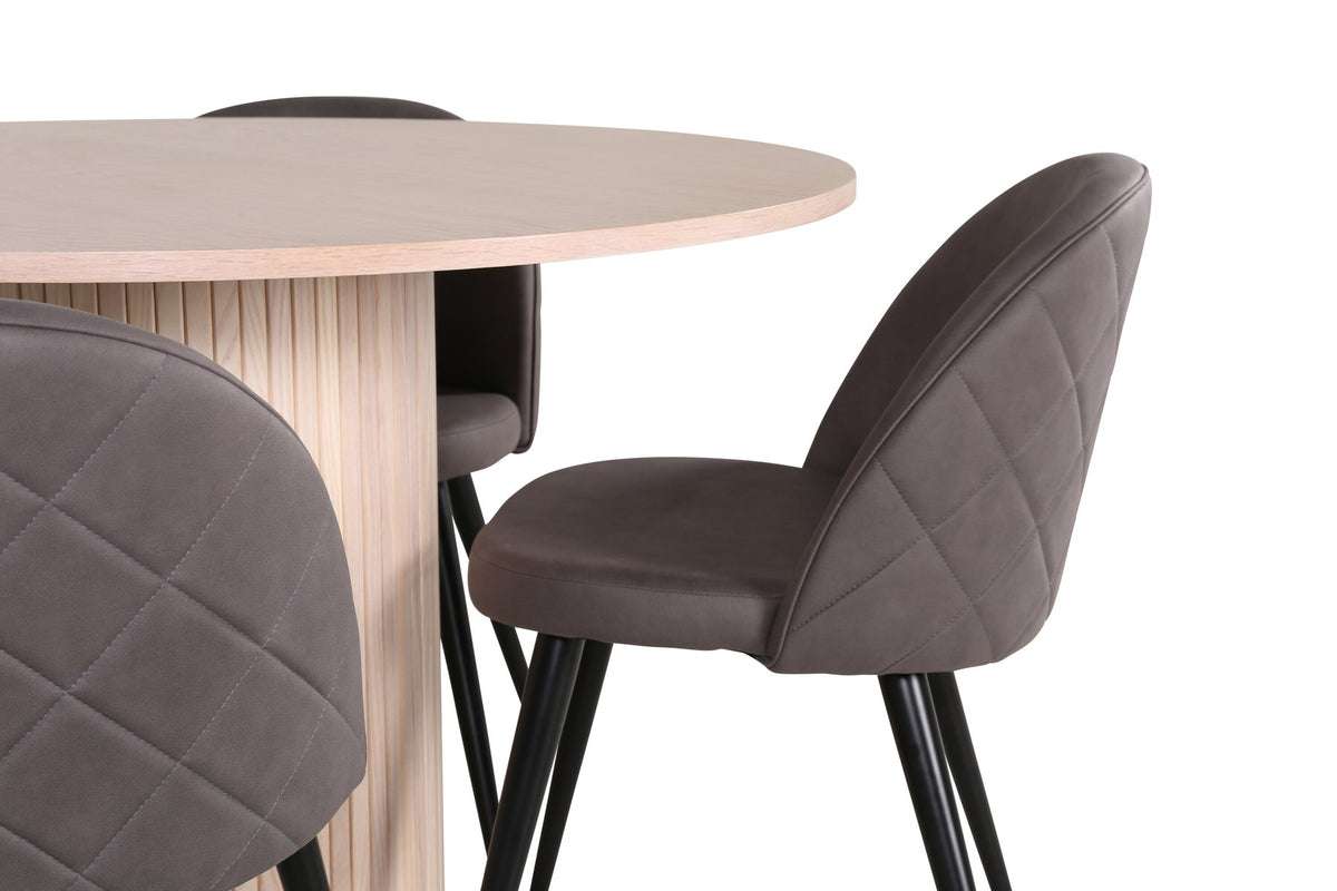 Runder Esstisch aus MDF in Whitewash mit ⌀110cm neben zwei Esszimmerstühlen mit grauem Mikrofaserstoff und schwarz pulverbeschichteten Eisenbeinen.