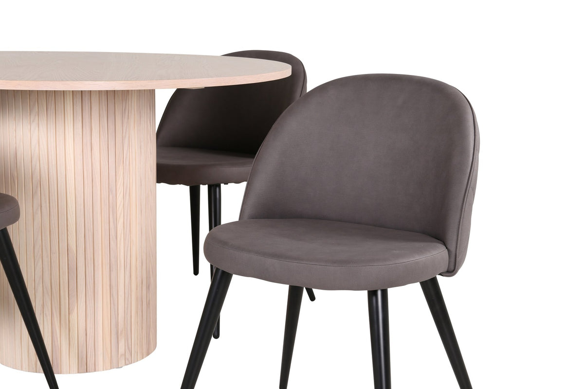 Runder Esstisch aus MDF in Whitewash mit ⌀110cm neben zwei Esszimmerstühlen mit grauem Mikrofaserstoff und schwarz pulverbeschichteten Eisenbeinen.