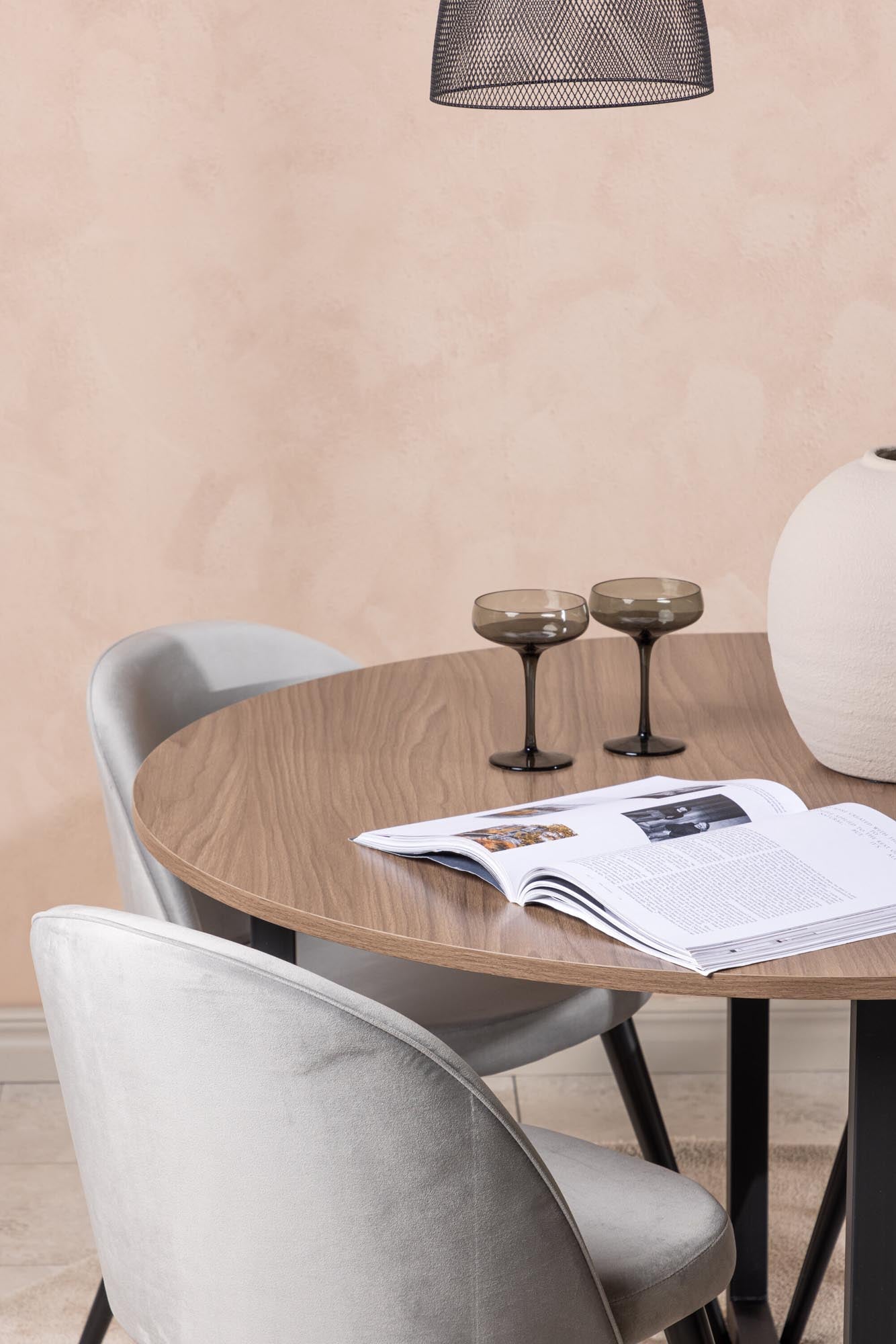 Elegantes Esszimmerset mit walnussfarbenem Tisch und grauen Samtstühlen, ideal für stilvolle und komfortable Mahlzeiten.