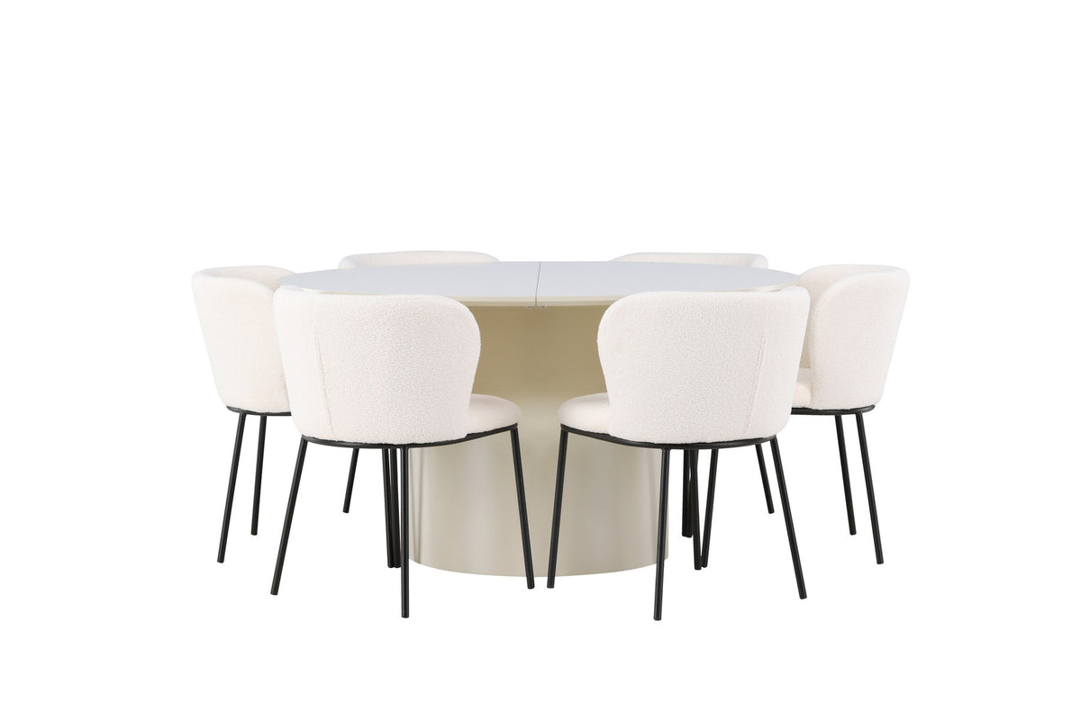Zwei weisse Esszimmerstühle mit Boucle-Bezug und schwarzen Metallbeinen neben einem runden Esstisch aus beigem MDF mit ⌀140 cm Durchmesser.
