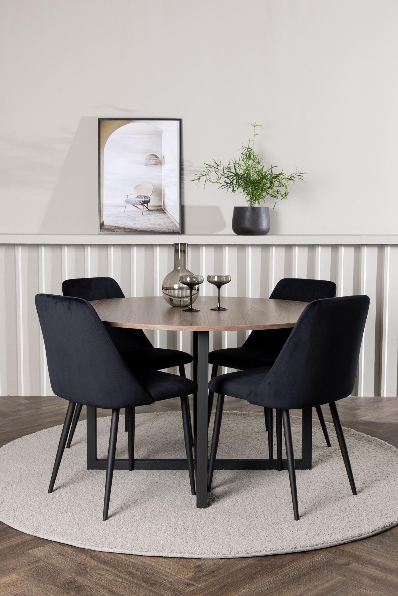 Stilvolles Durango Esszimmerset: Runder Tisch in Walnussoptik, schwarze Stahlbeine, samtbezogene Stühle. Skandinavisches Design für gesellige Runden.