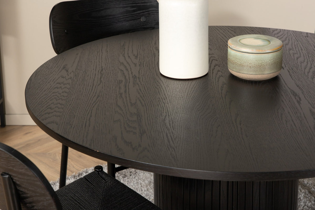 Rundes Esszimmerset Bianca mit Stuhl Polly: Tisch aus MDF und Furnier in Walnuss, vier schwarze Stühle mit Metallbeinen und Seilsitzen.