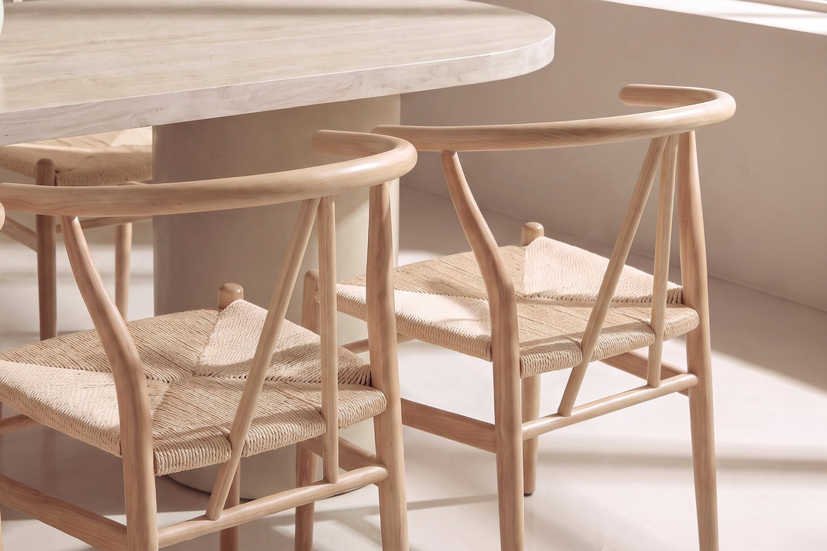 Ovaler Esstisch mit MDF-Tischplatte in Beige und Stahlbeinen, umgeben von stapelbaren Esszimmerstühlen mit Rattan-Geflecht und Stahlgestell in Holzoptik.