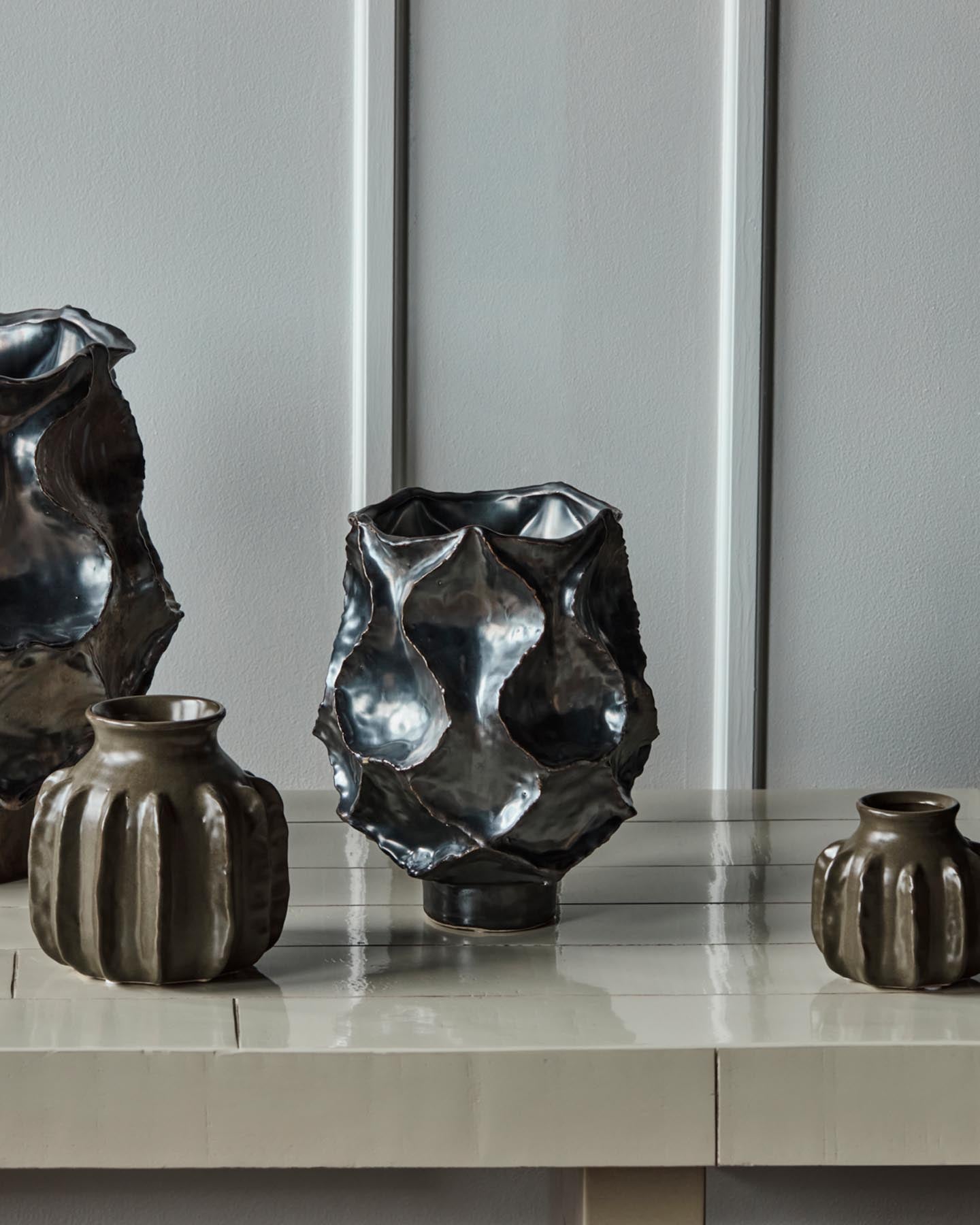 Verleihen Sie Ihrem Zuhause mit der einzigartigen Vase HDWaves von House Doctor einen Hauch von Eleganz. Handgefertigt aus robustem Steinzeug, besticht sie durch ihre antikmetallische Glasur und geschwungene Form. Ideal für Blumen oder als Kunstobjekt.