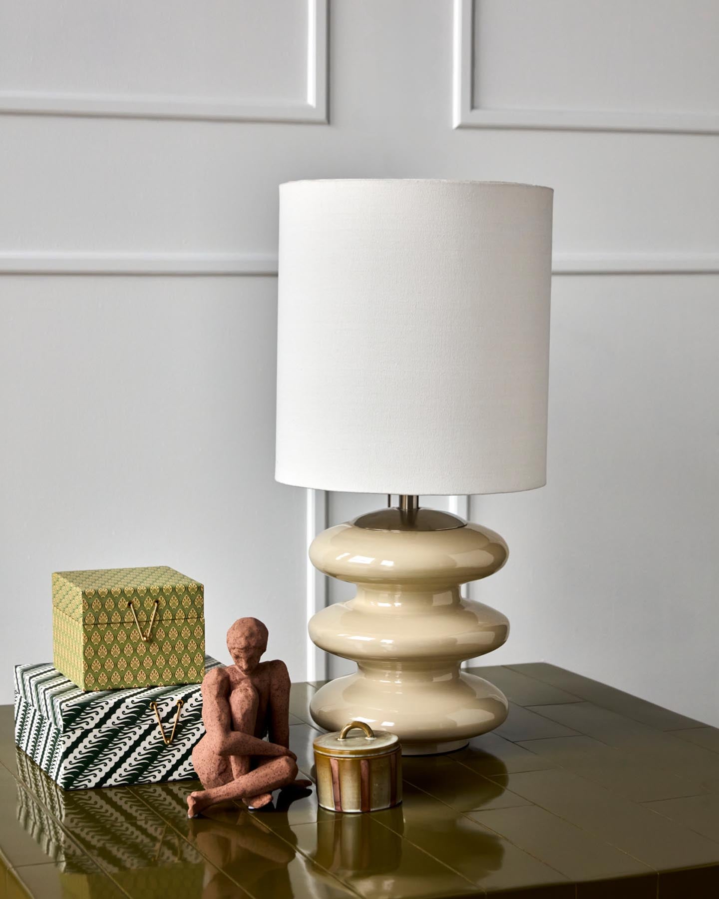 Verleihen Sie Ihrem Raum mit der stilvollen Tischleuchte HDStep von House Doctor in Sand/Off-White einen Hauch von Eleganz. Ihr einzigartiges Glasdesign und der weiche Baumwollschirm sorgen für eine einladende Lichtstimmung.