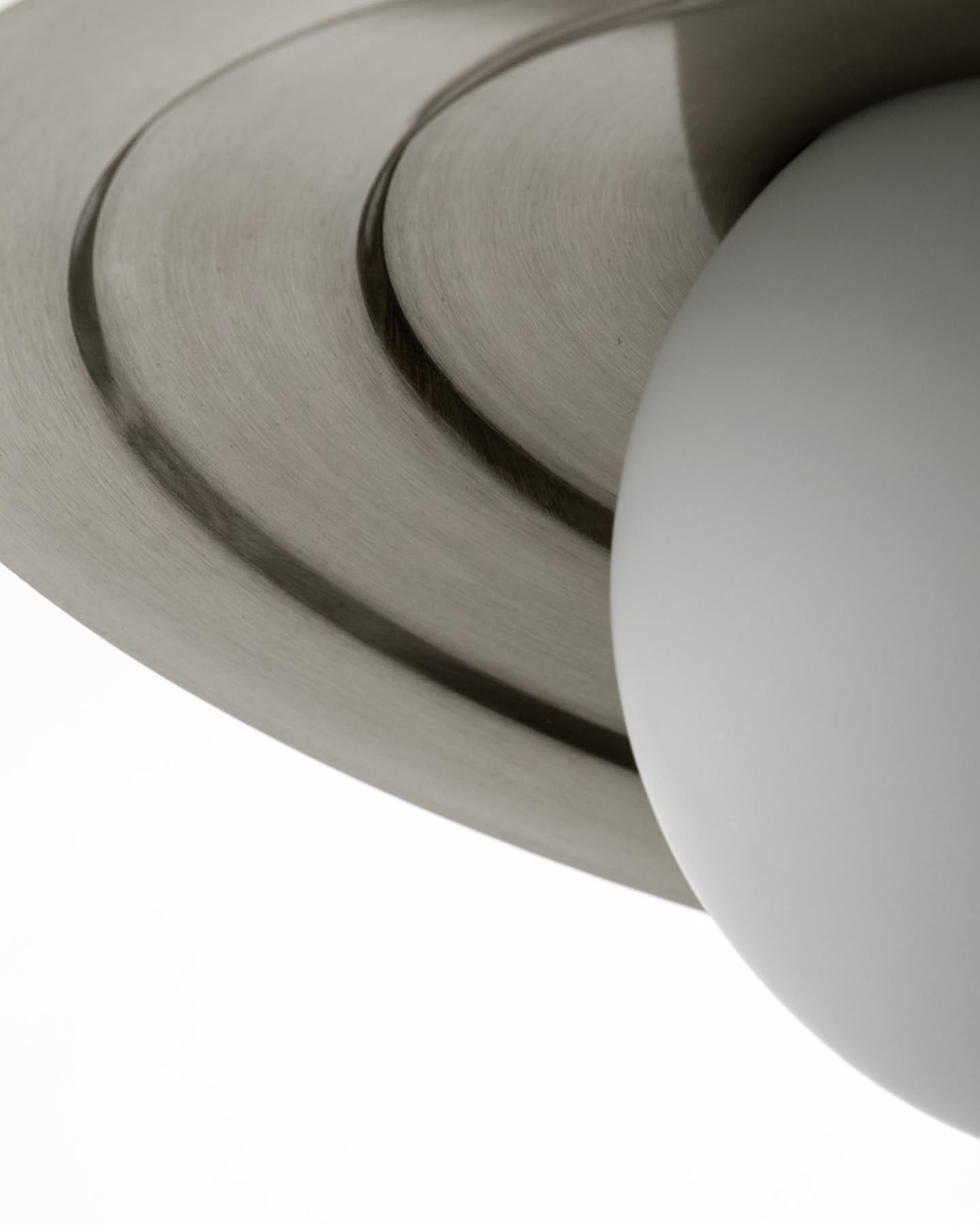 Die HDCoin Pendelleuchte von House Doctor kombiniert edles gebürstetes Silber mit mattem Glas und verleiht jedem Raum einen modernen, einladenden Look.