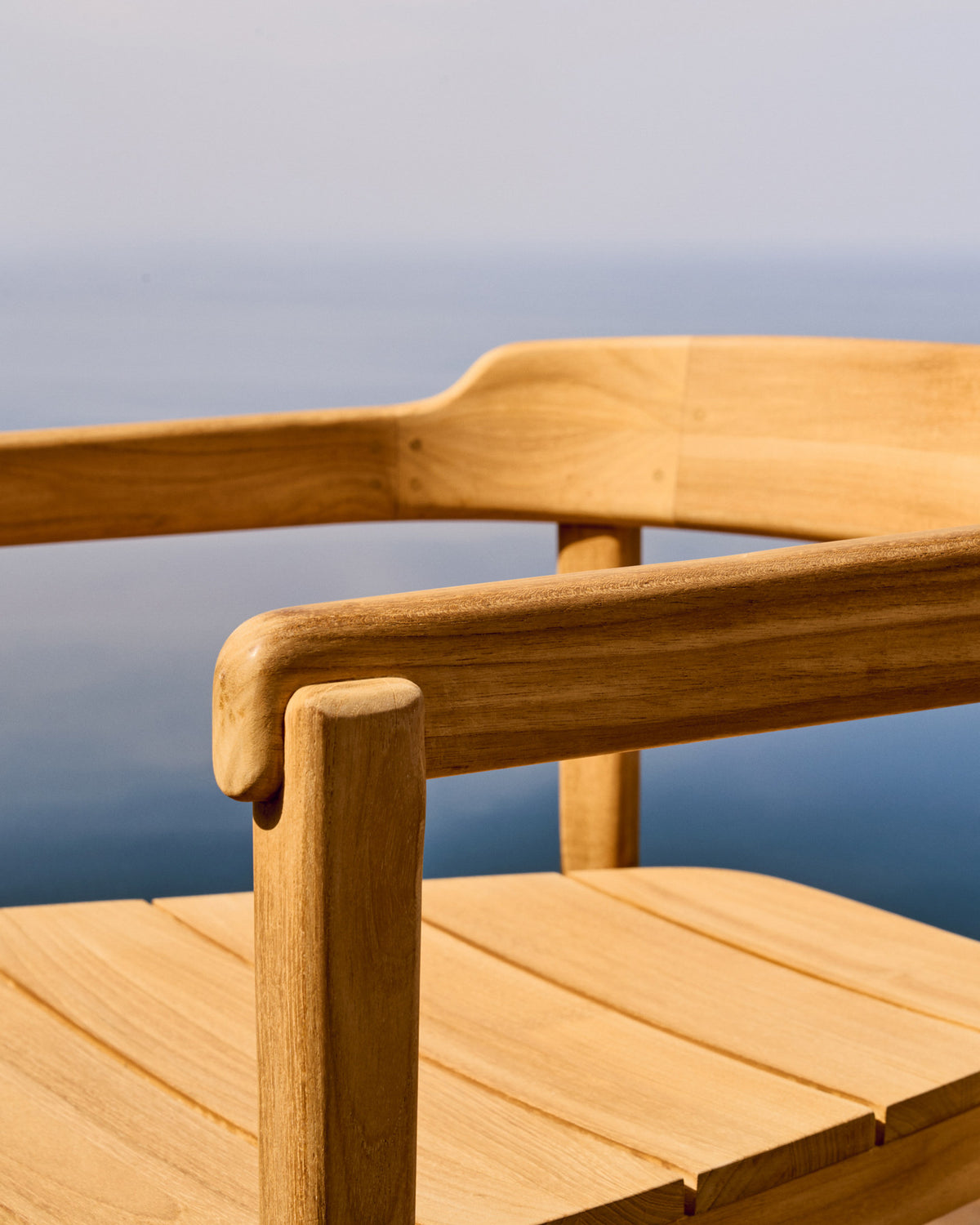 Stapelbarer Stuhl Icaro aus massivem Teakholz mit natürlichem Finish FSC 100% in Natur präsentiert im Onlineshop von KAQTU Design AG. Gartenstuhl mit Armlehnen ist von Kave Home