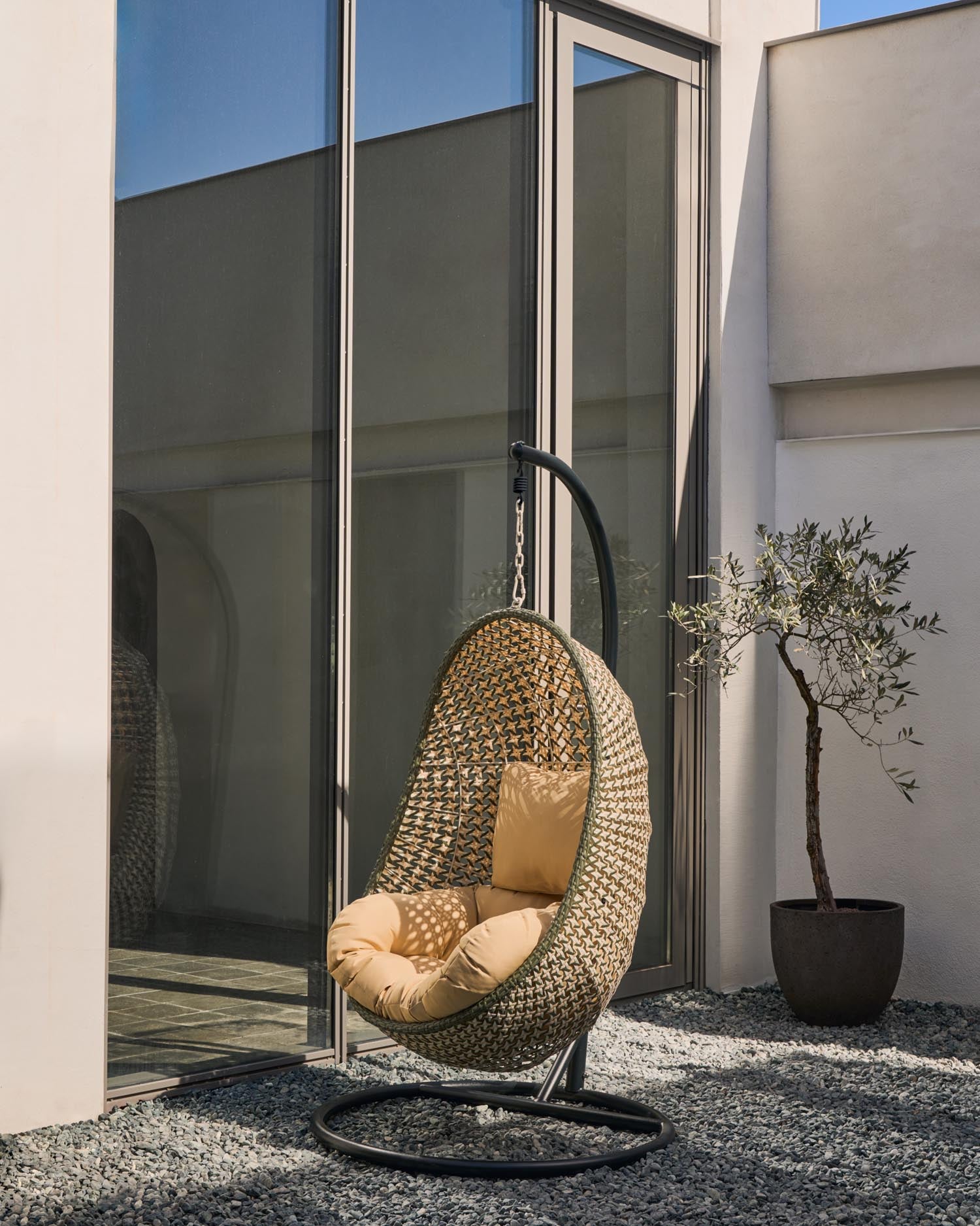 Hängesessel Cira von Kave Home: Stilvolles Poly-Rattan, stabiler Dunkelgrau Standfuss, komfortable Kissen. Perfekt für drinnen und draußen!