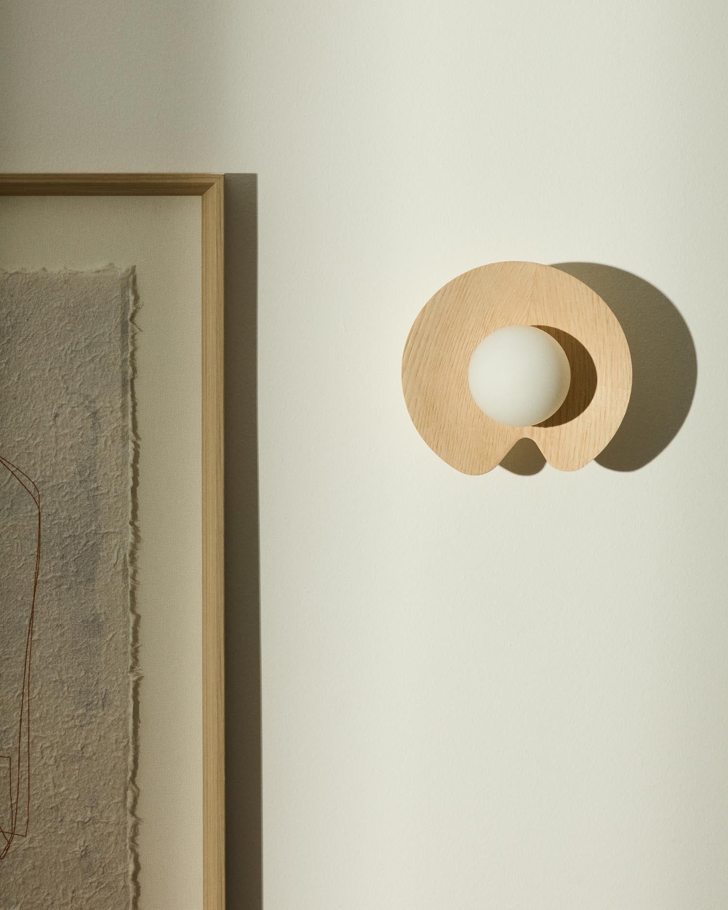 Entdecken Sie die Wandleuchte Wilara von Kave Home: Eichenfurnier trifft auf elegante weiße Rauchglaskugel für stilvolle Akzente in jedem Raum.