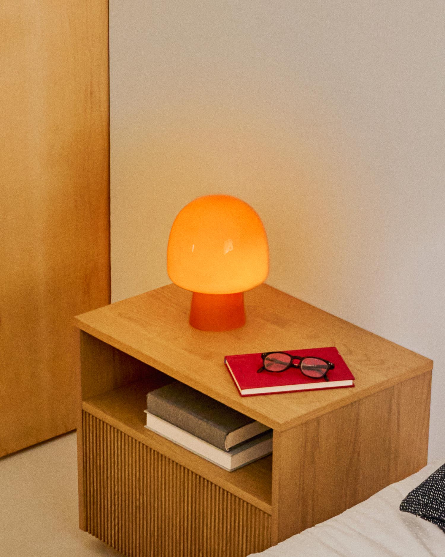 Die Tischleuchte Reig aus orangefarbenem Glas vereint Retro-Design mit moderner Eleganz und schafft ein warmes Ambiente.
