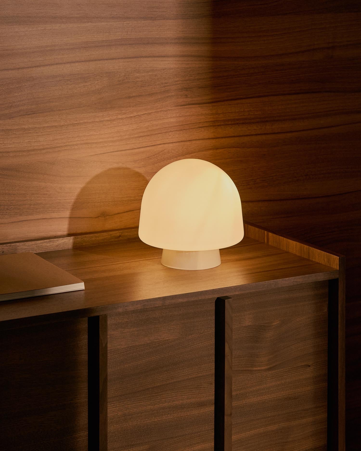 Stilvolle Tischleuchte Reig aus grauem Glas und Holz, vereint modernes Design mit Retro-Charme für einladende Wohnräume.