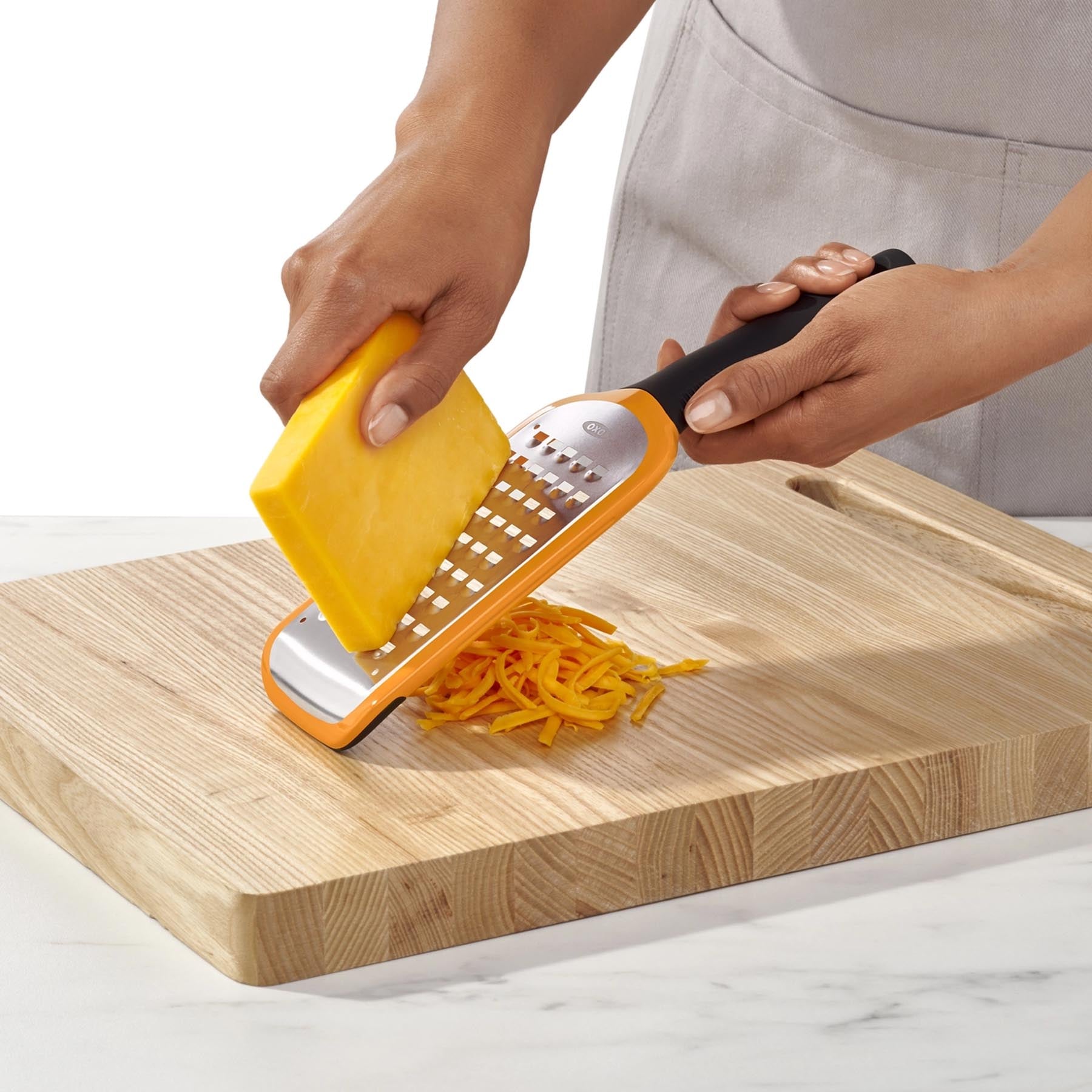 Helle, grob geätzte Reibe von OXO in Orange, perfekt für das einfache Reiben von Käse und Gemüse. Ein unverzichtbares Werkzeug für jede Küche.