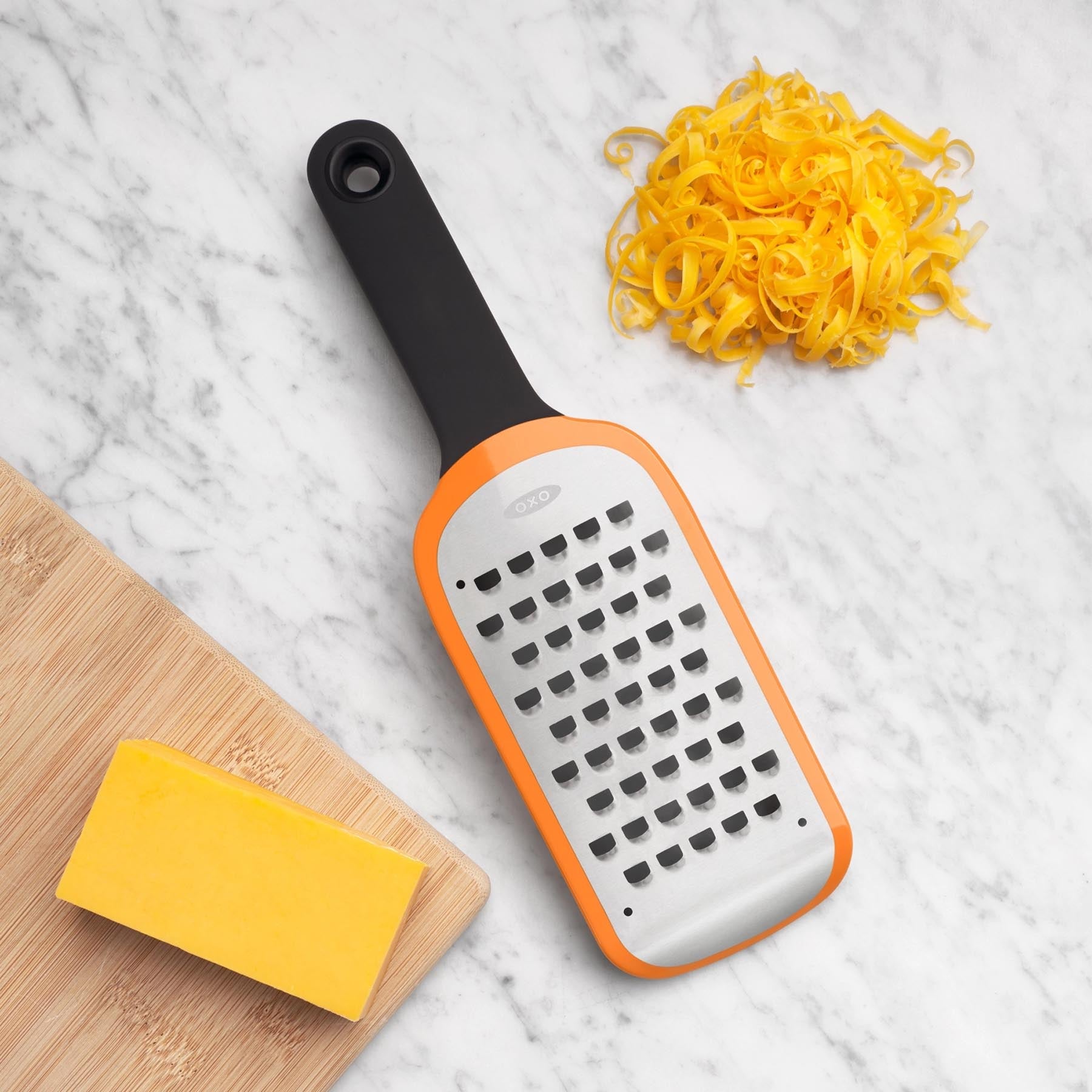 Grob geätzte Reibe von OXO in leuchtendem Orange, ideal zum mühelosen Reiben von Käse und Gemüse. Ein praktisches Küchenutensil für kreative Köche.