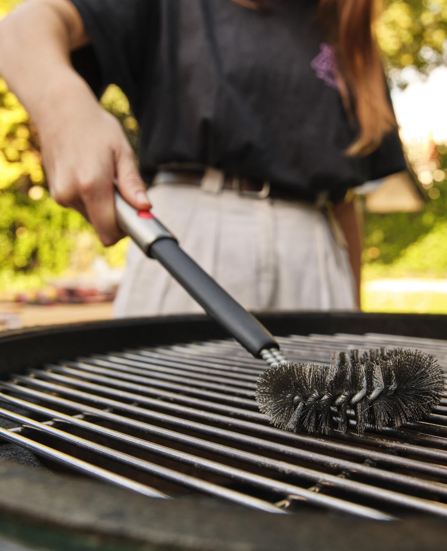 Effiziente Grillreinigung mit der Joseph Joseph GrillOut Bürste, die einen einziehbaren Kopf für mühelosen Zugang zu schwer erreichbaren Stellen bietet.