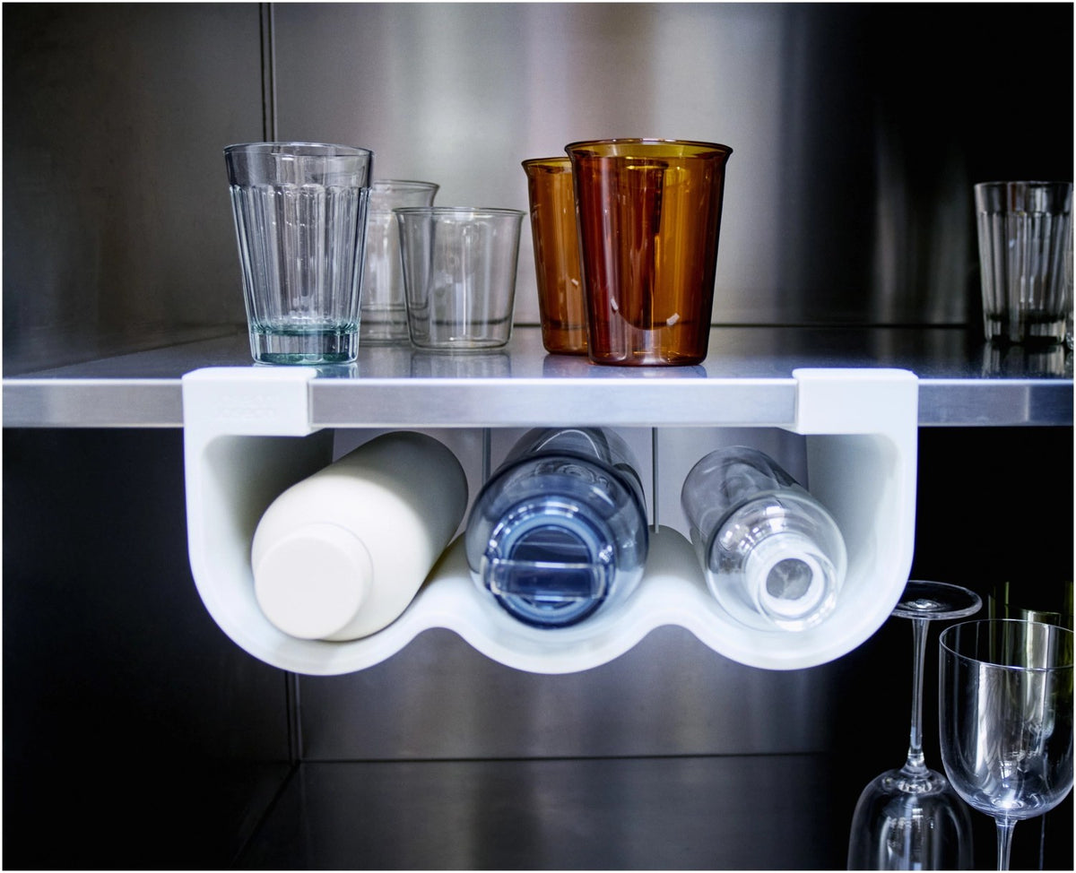 Graue Küchenhalterung CupboardStore von Joseph Joseph, montiert unter einem Regal, mit Platz für drei Flaschen oder Becher aus Kunststoff.
