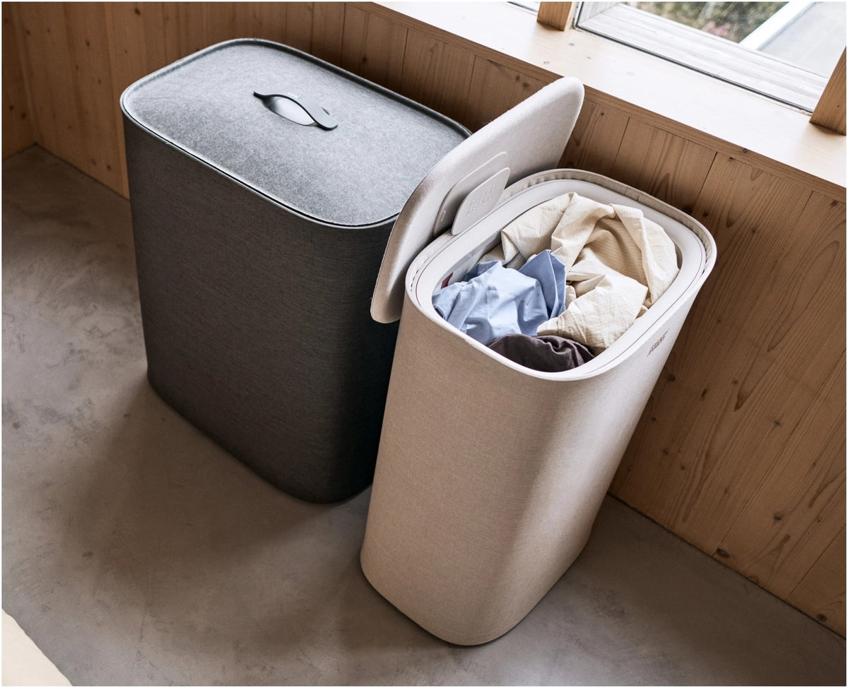 Grauer Wäschetrennkorb Tota One 60l von Joseph Joseph mit seitlichem Filzdeckel und herausnehmbarer Tragetasche für die Wäsche.
