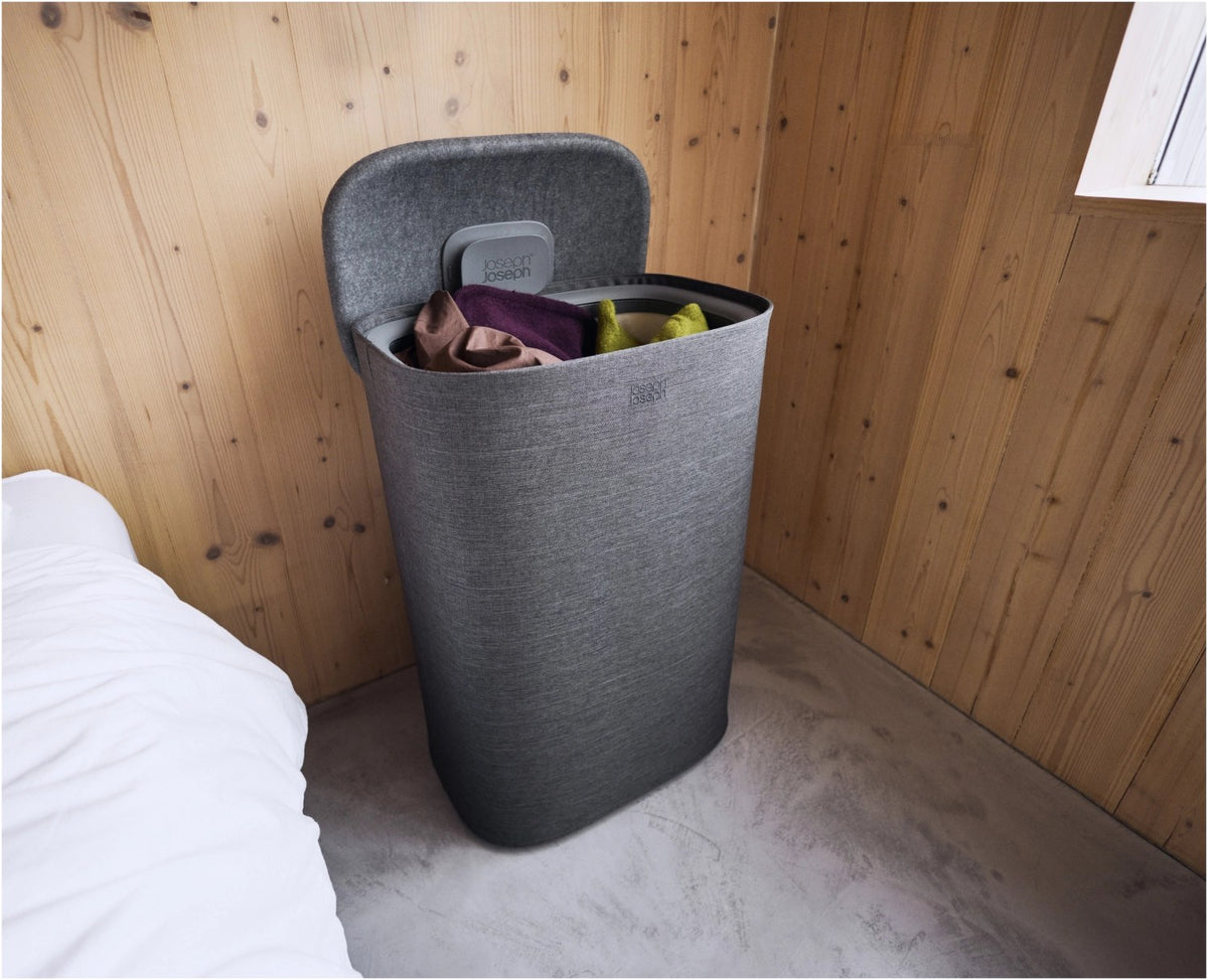 Grauer Wäschetrennkorb Tota One 60l von Joseph Joseph mit seitlichem Filzdeckel und herausnehmbarer Tragetasche für die Wäsche.