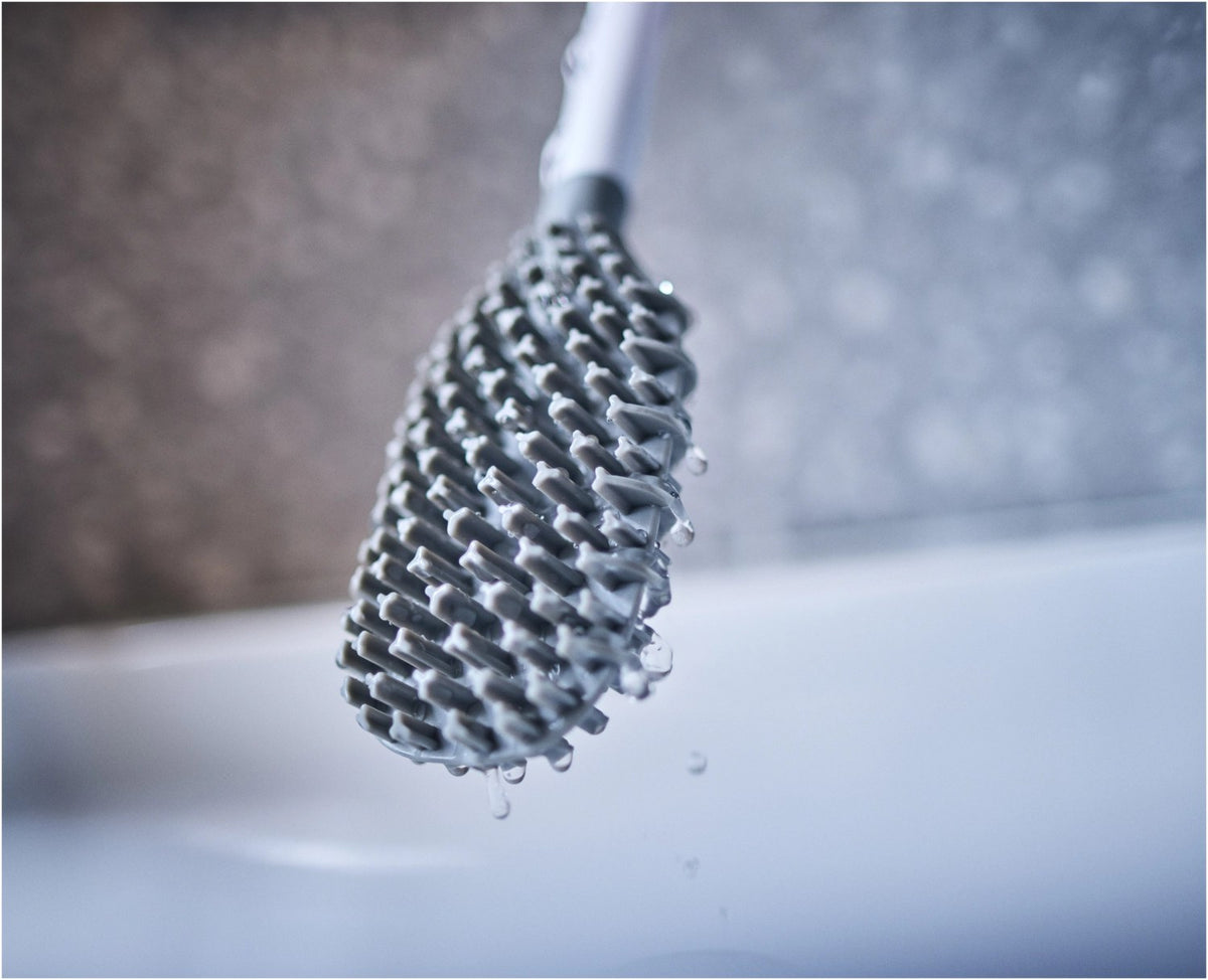 Weisse WC Bürste mit dreifach beklingten Borsten und passendem kompaktem Halter, glänzende Oberfläche, schlanke zylindrische Form.