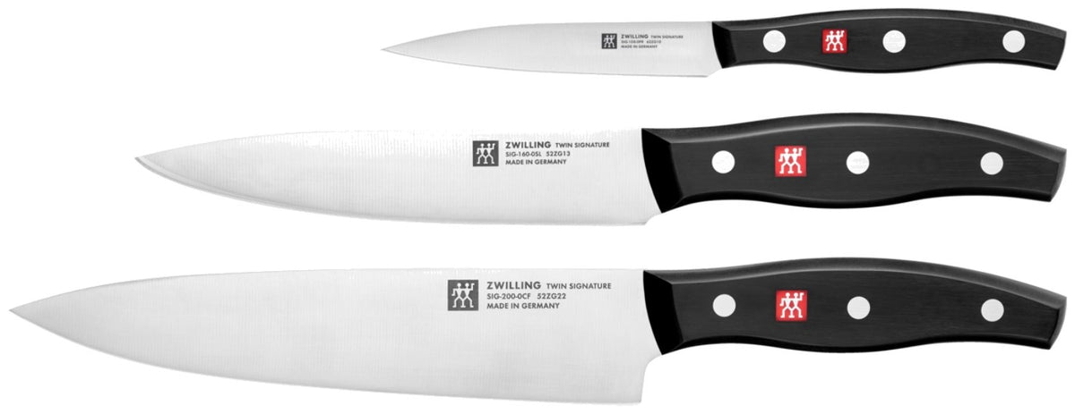 Drei Küchenmesser aus Edelstahl mit Drei-Nieten-Griff: Schälmesser, Tranchiermesser und Kochmesser der Zwilling Signature Serie, nebeneinander liegend.