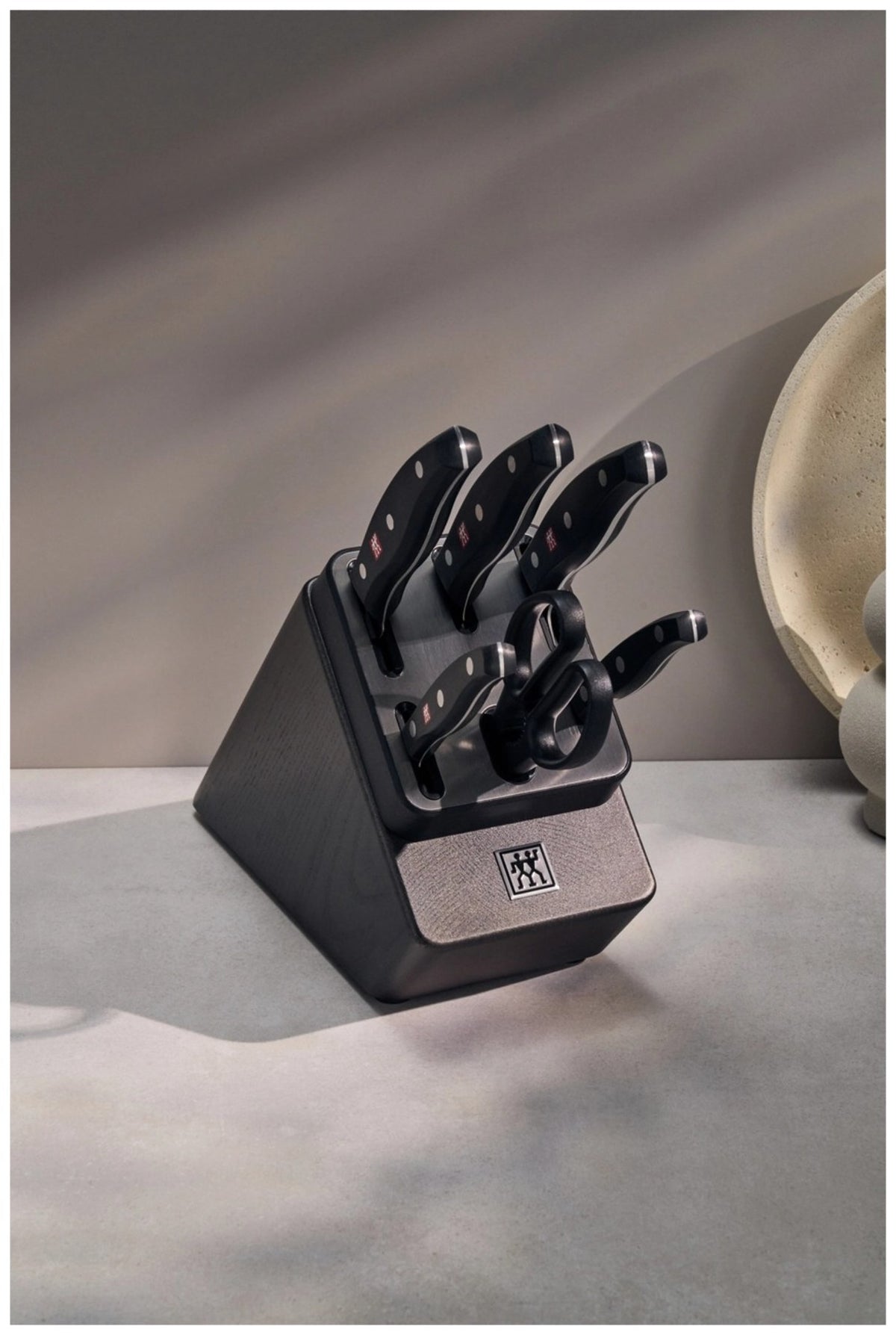 Schwarzer Messerblock aus Kunststoff mit fünf eingesteckten Edelstahlmessern und einer Vielzweckschere, Drei-Nieten-Griffdesign sichtbar.